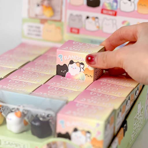 Hand reaching for a small box among a collection of colorful boxes with cartoon designs.