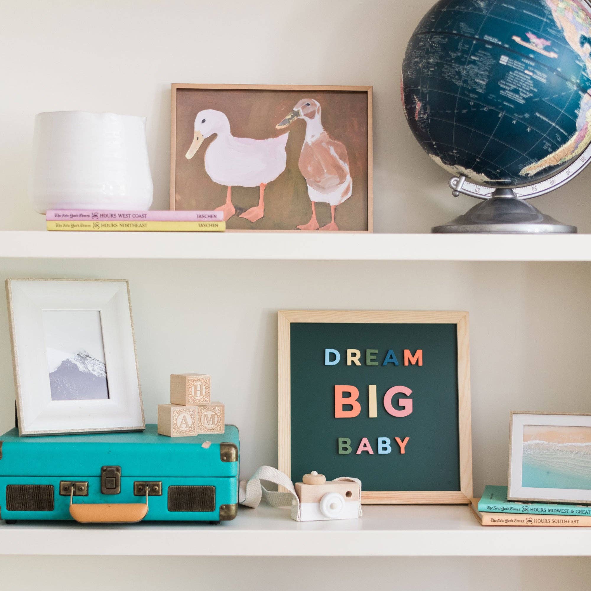 Decorative shelf with a 'Dream Big Baby' sign, globe, books, and toys.