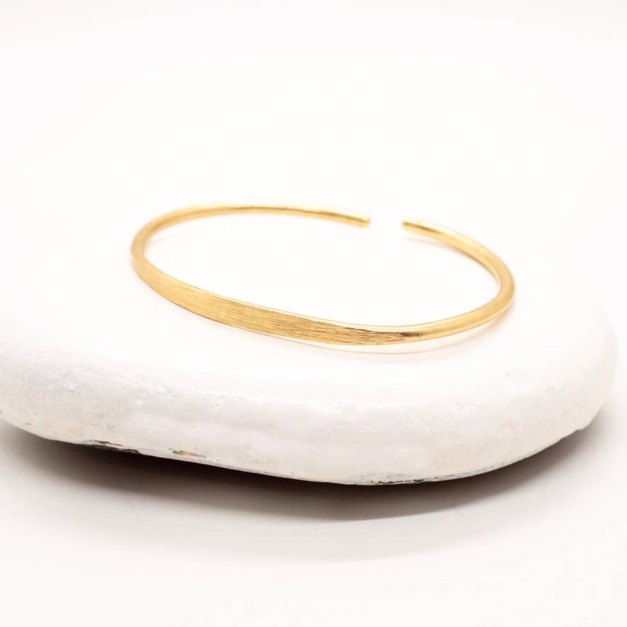 Gold bracelet on a white stone surface