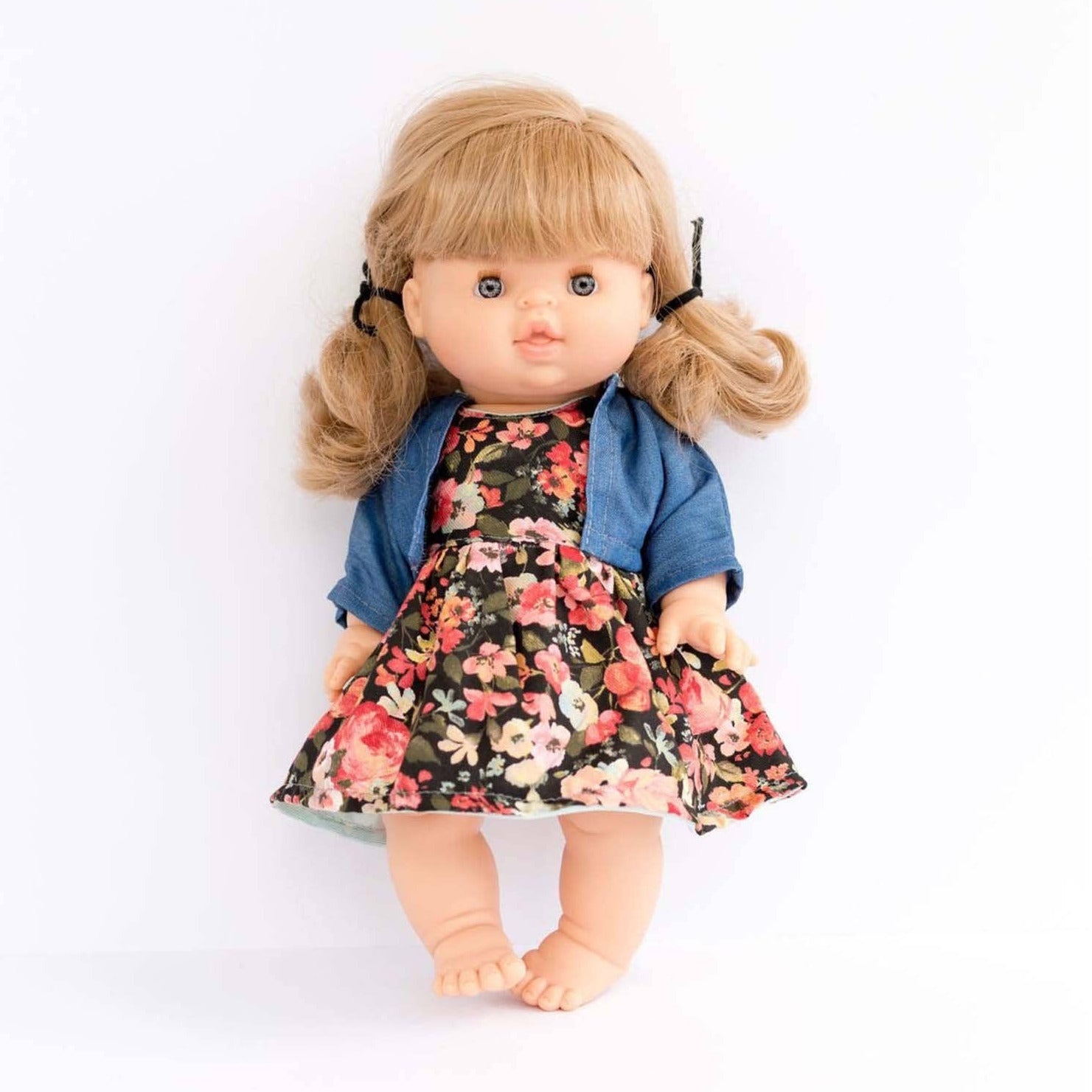 Doll wearing a floral dress and denim jacket on a white background