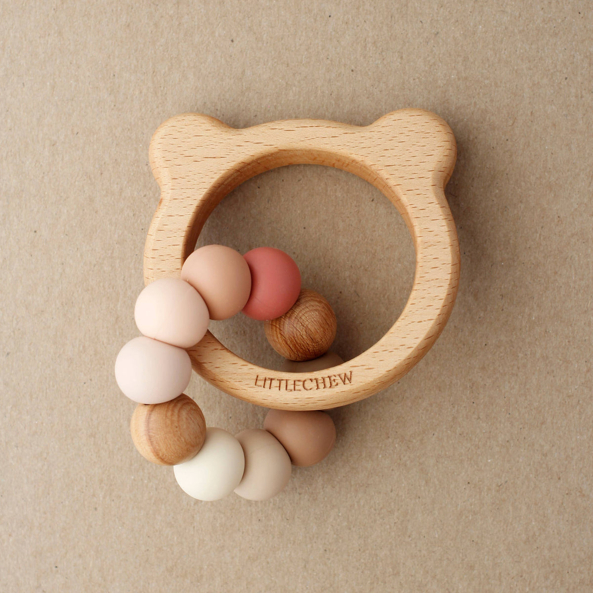 Wooden teething ring with colorful beads on a beige background