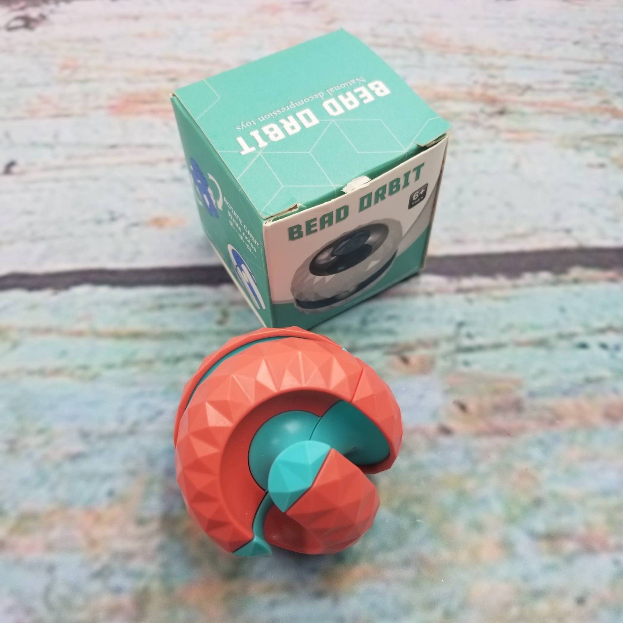 Red and green geometric toy with packaging on a textured surface