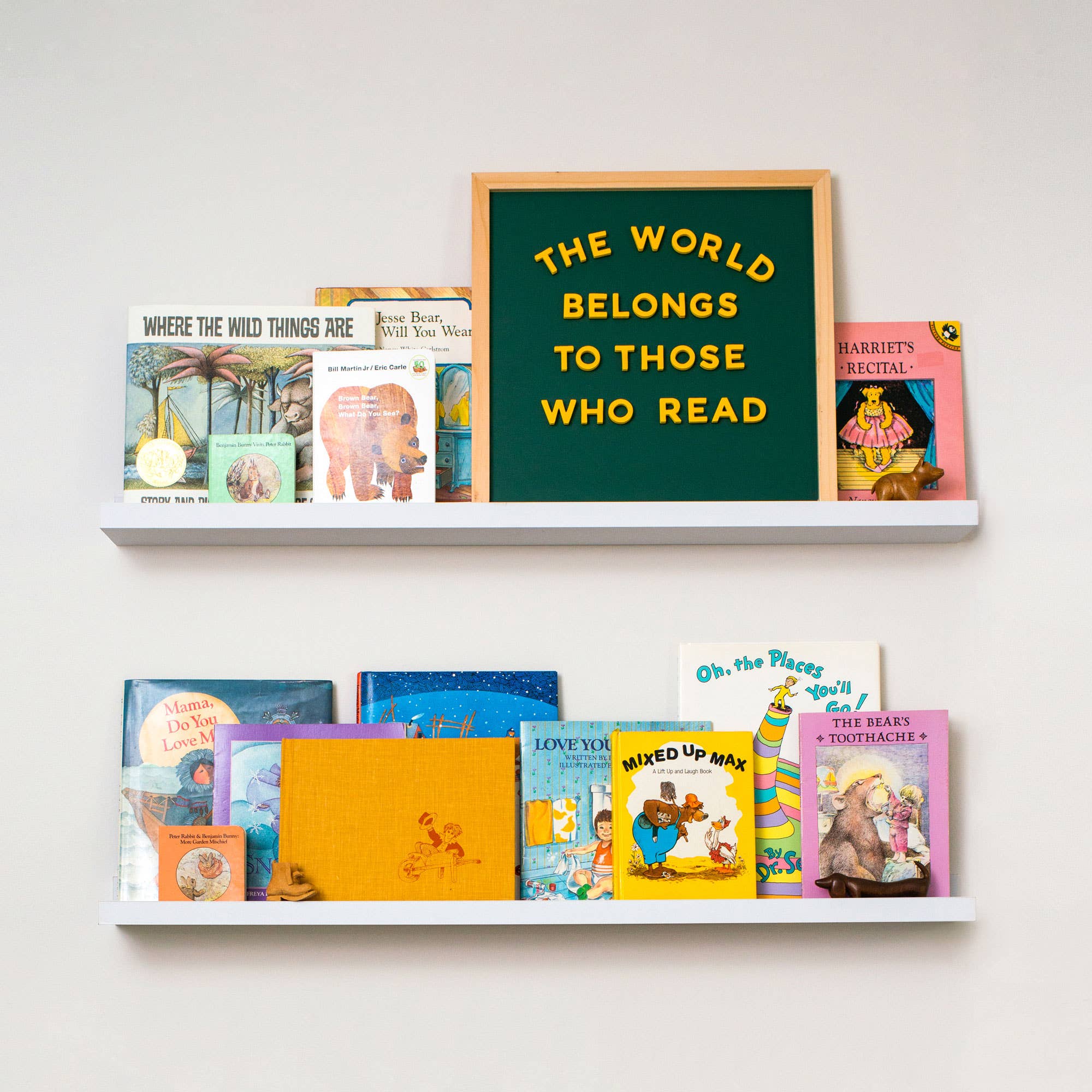 Shelves with children's books and a framed quote on a white wall