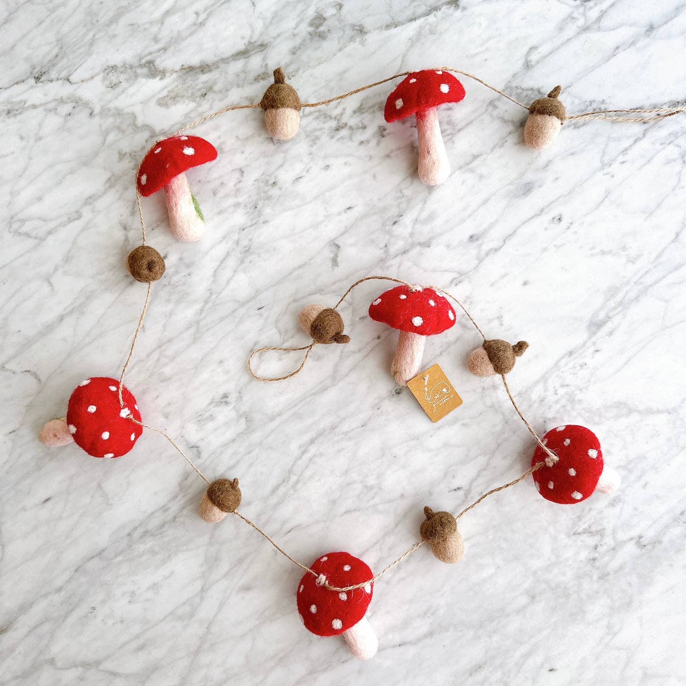Decorative garland with red mushroom-shaped ornaments on a marble surface