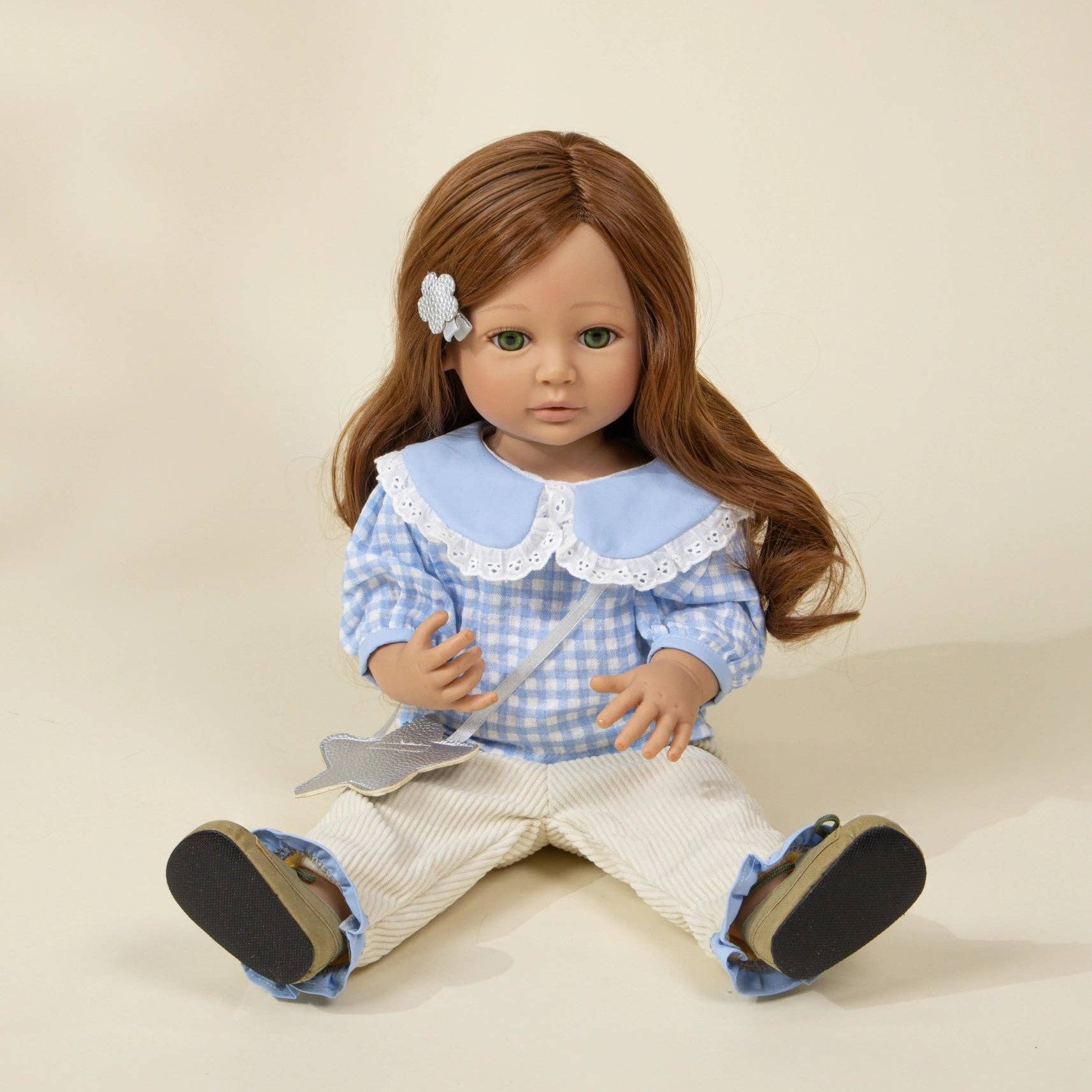 Doll with long brown hair wearing a blue checkered dress and white shoes on a beige background