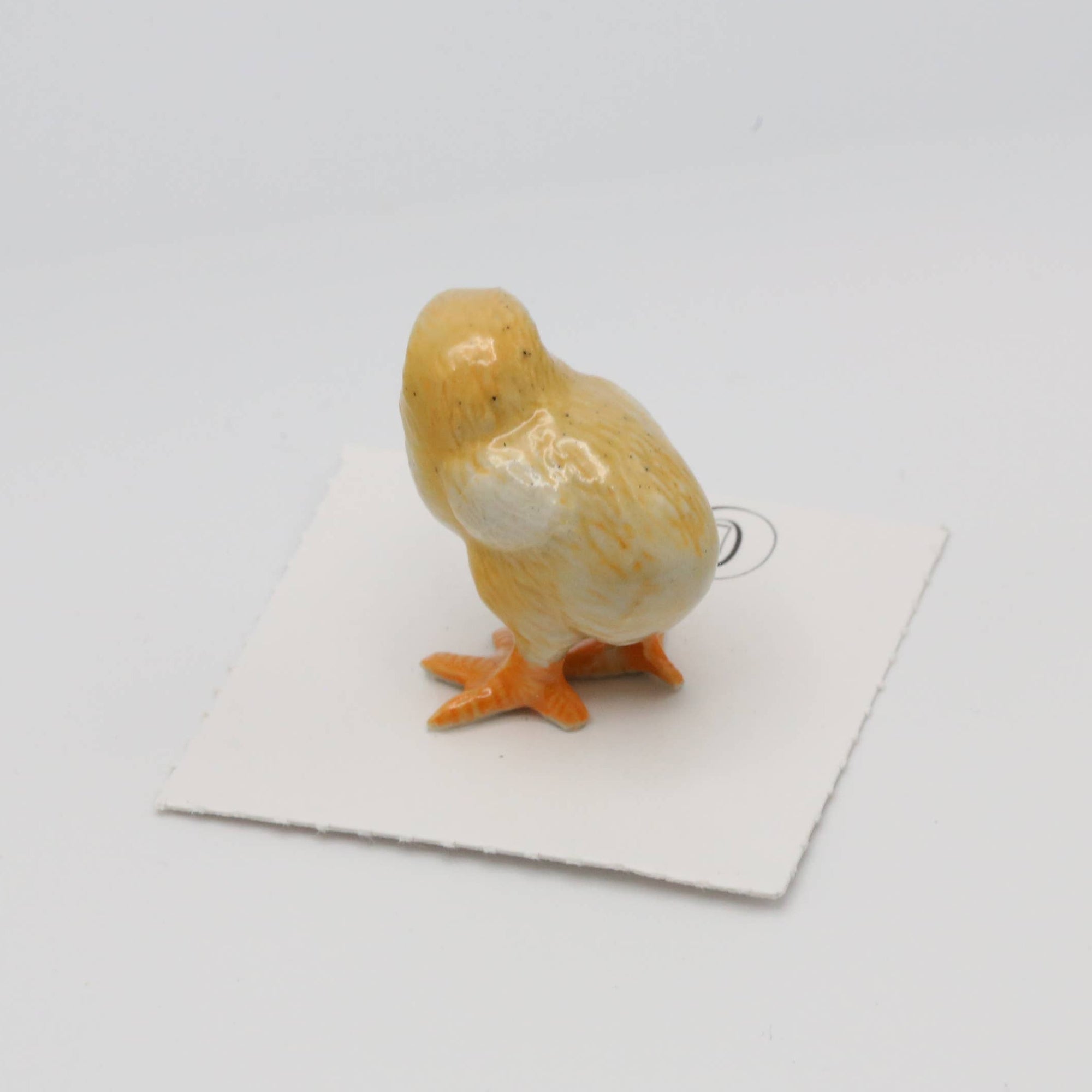 Small ceramic duck figurine on a white card with a white background