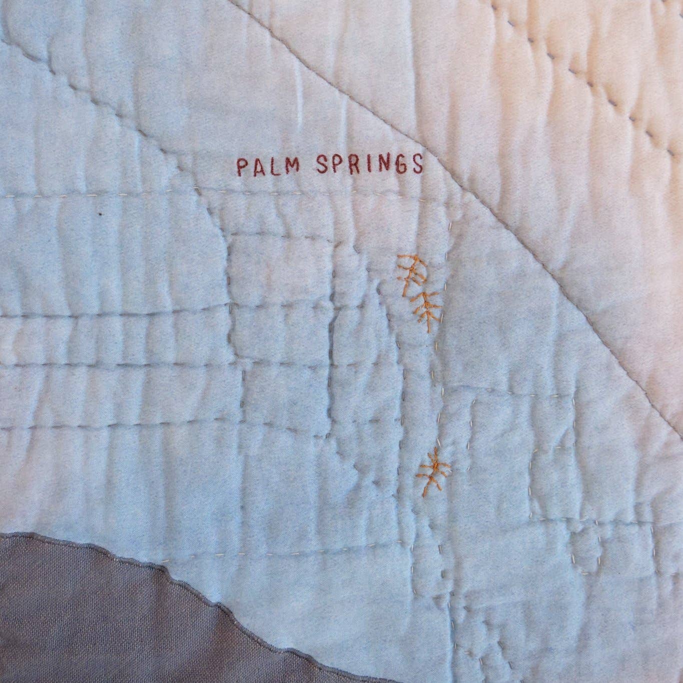 Textile with 'Palm Springs' embroidered on a textured fabric background