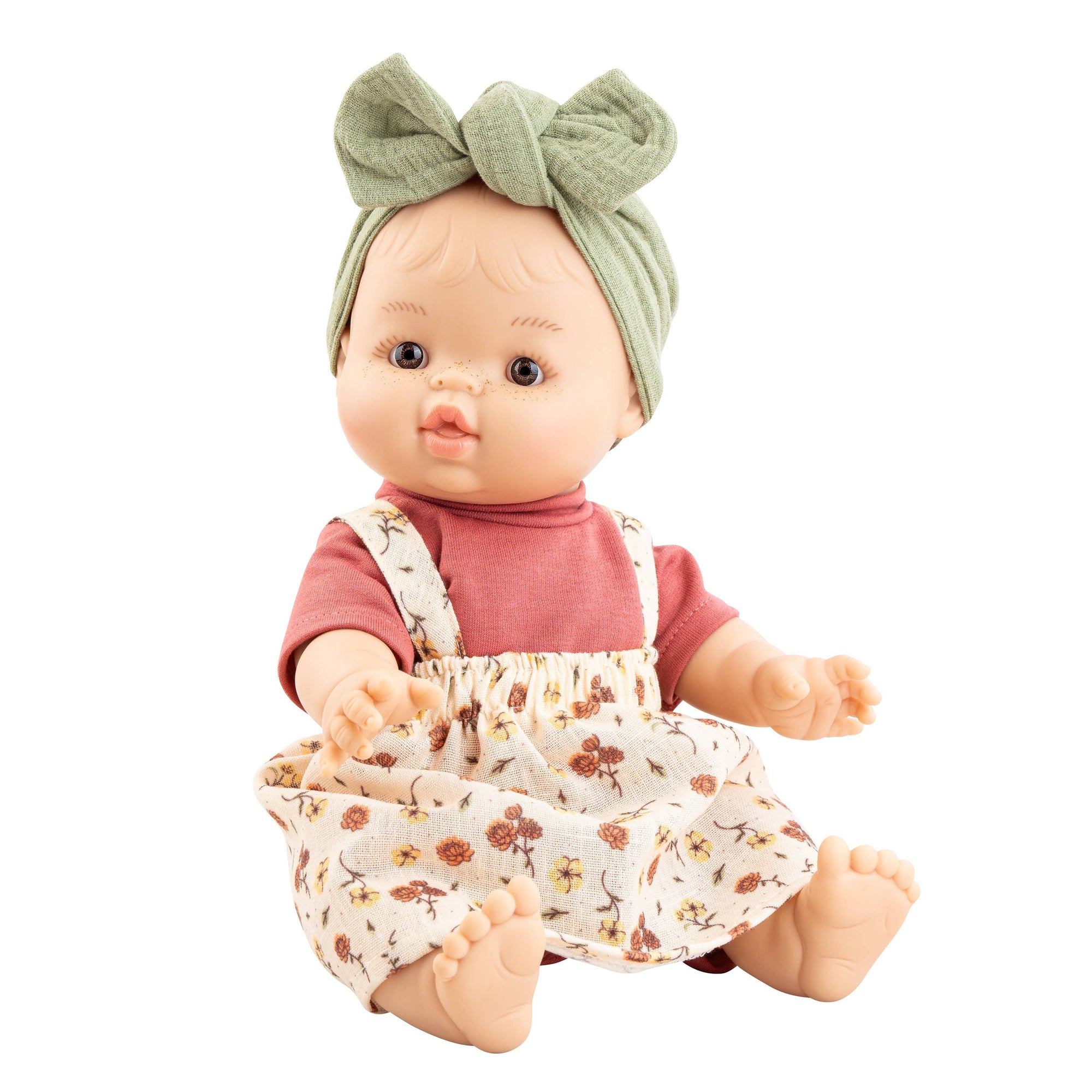 Baby doll with a pink shirt and floral overalls on a white background