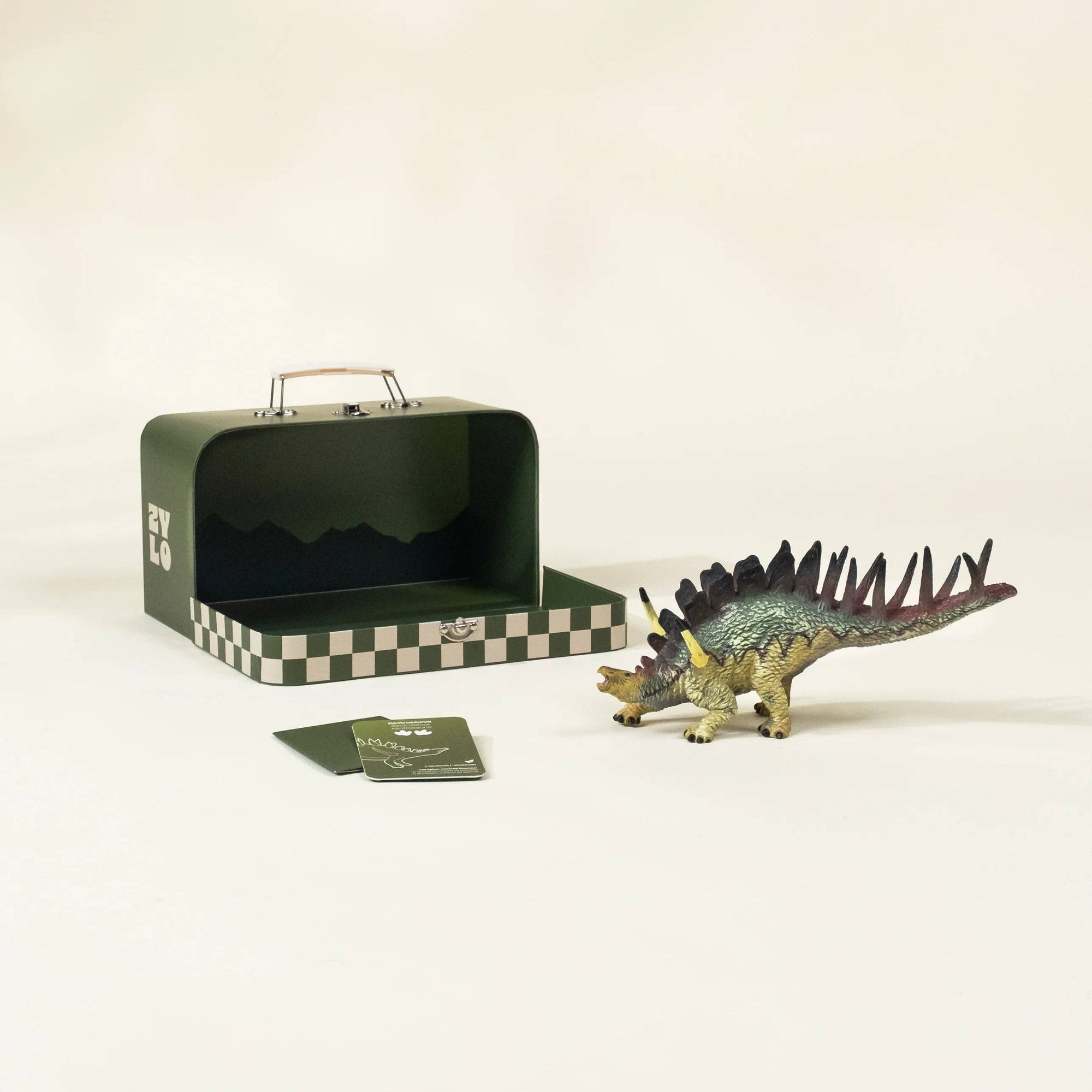 Dinosaur toy figure next to a green checkered suitcase on a beige background