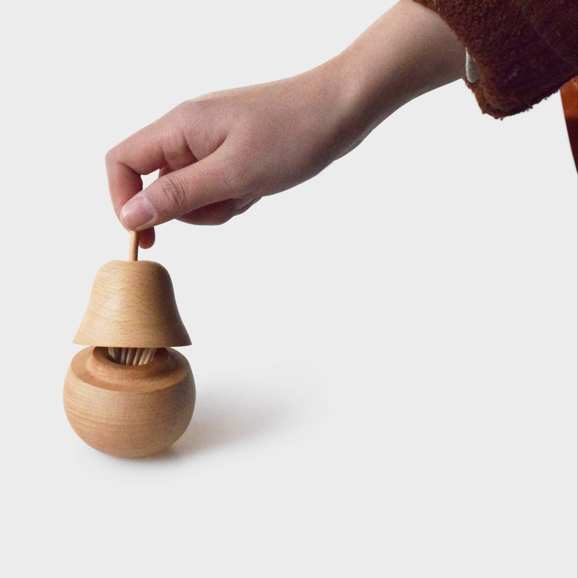 Wooden tooth pick holder being held by a hand on a white background