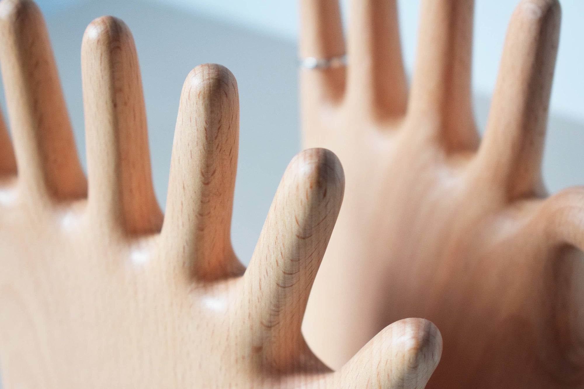 Wooden hand-shaped ring holder with a blurred background