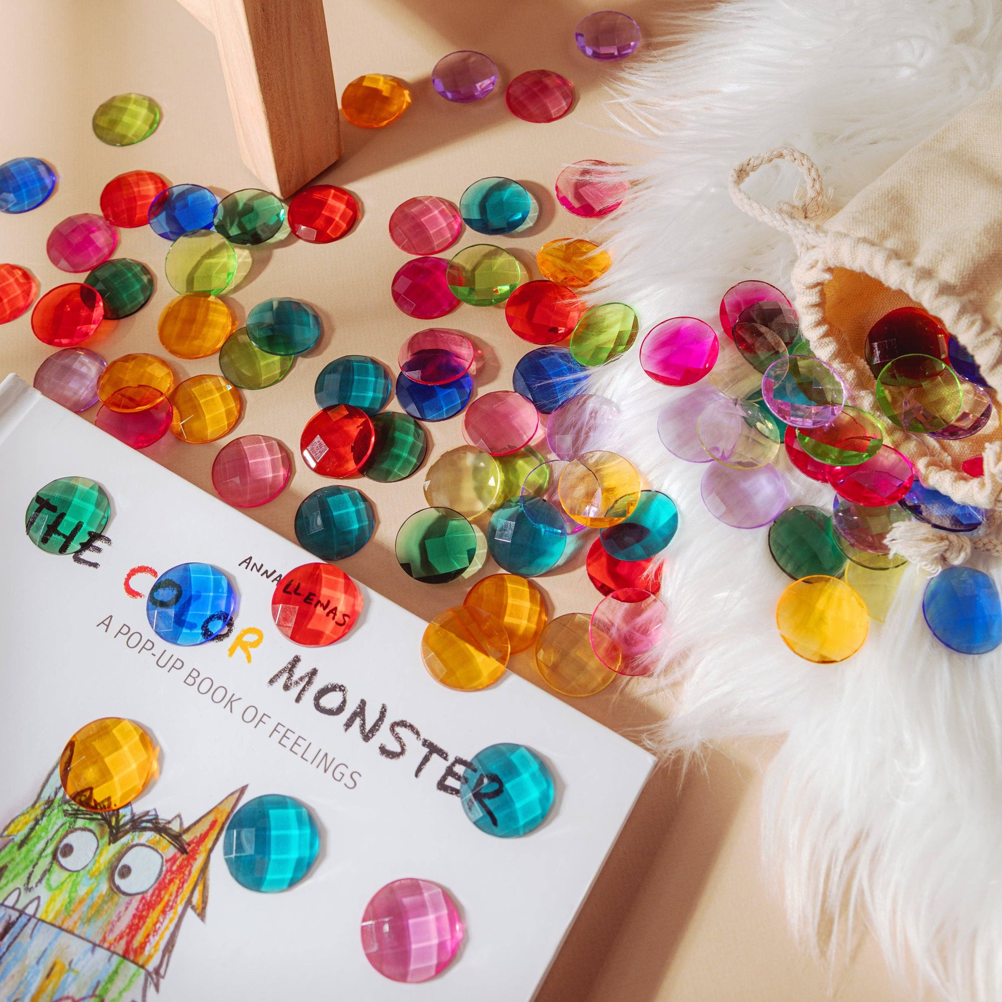 Colorful gemstones scattered on a surface next to a book titled 'The Color Monster'.