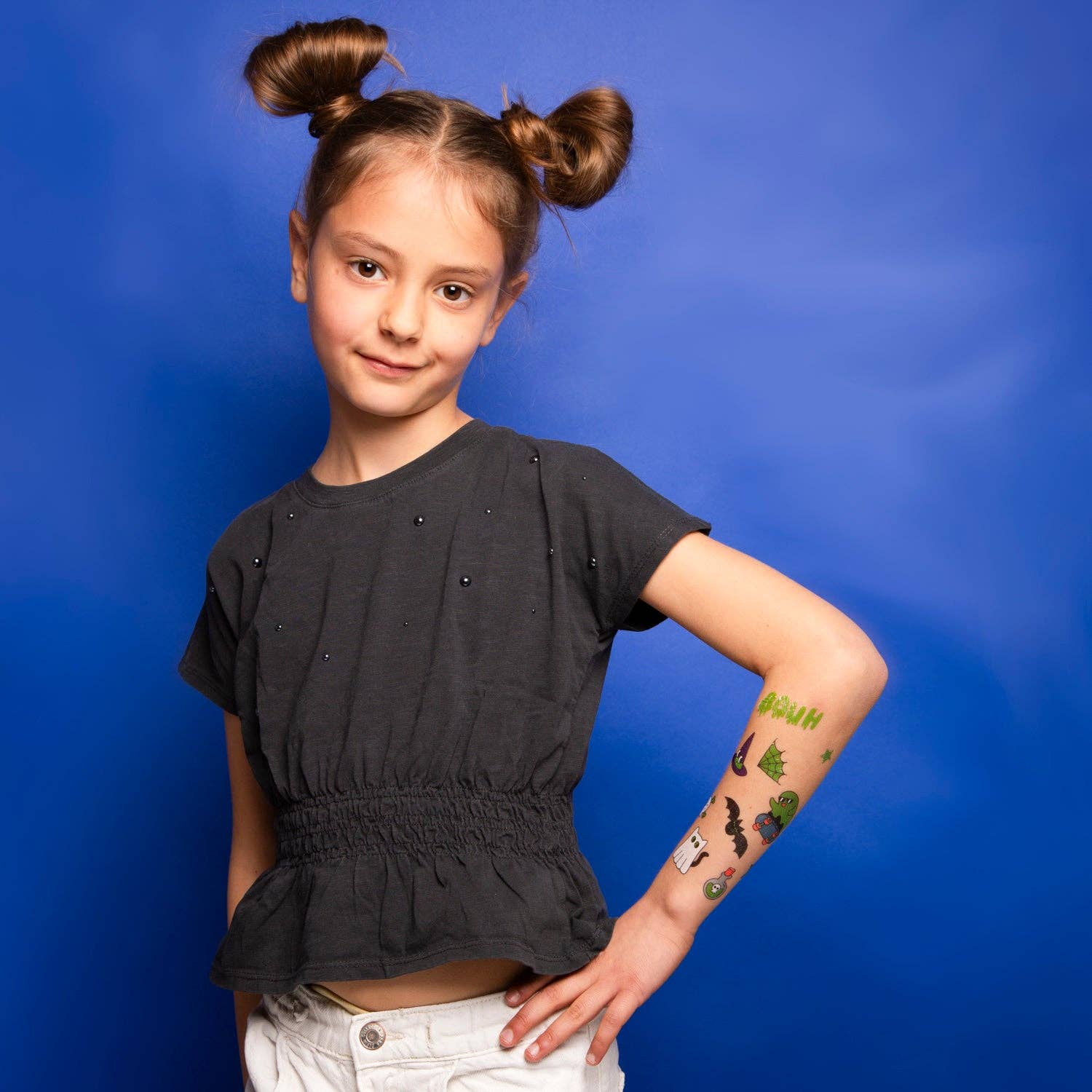 Young girl with a black top and white pants against a blue background