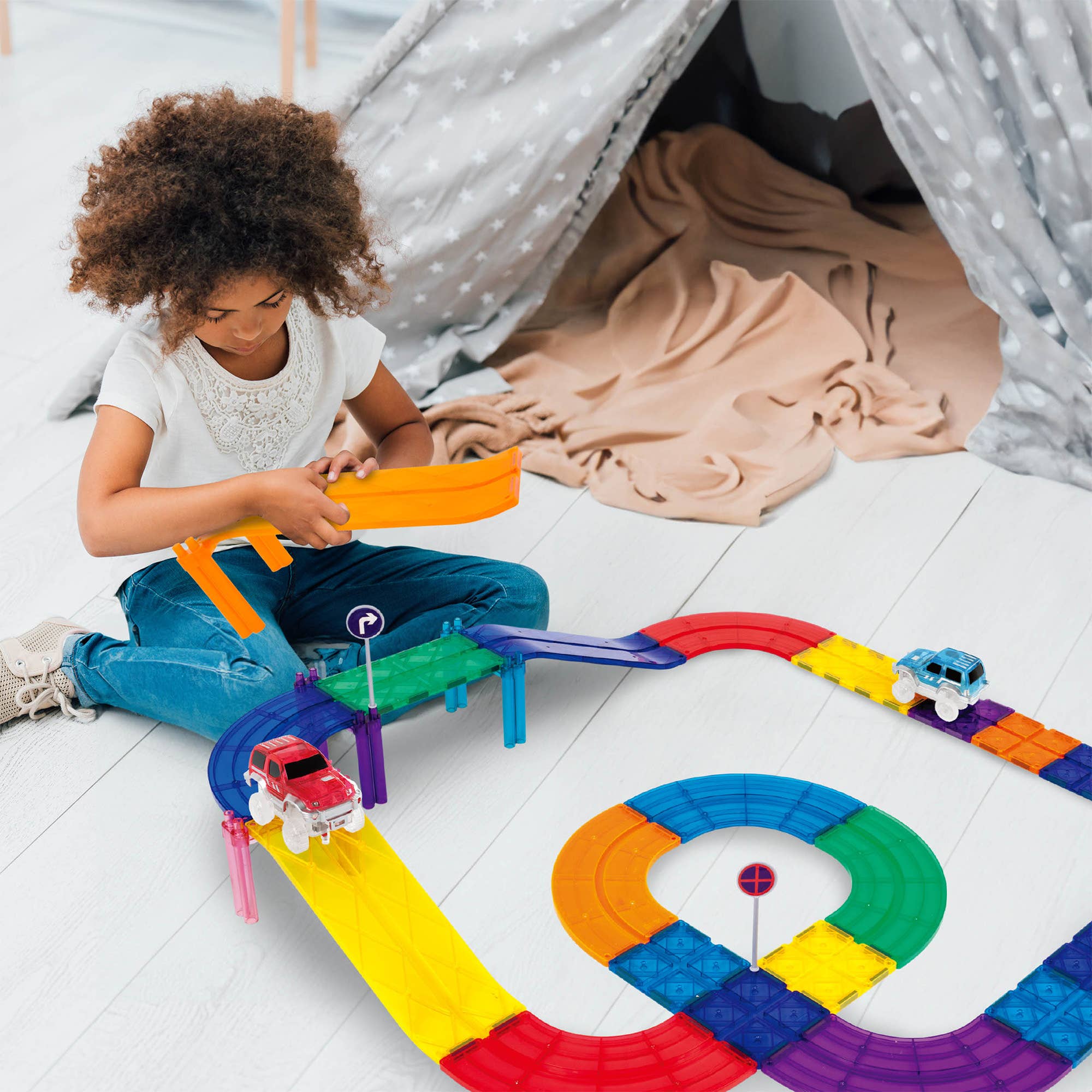 Child playing with a colorful toy track set on a white floor.