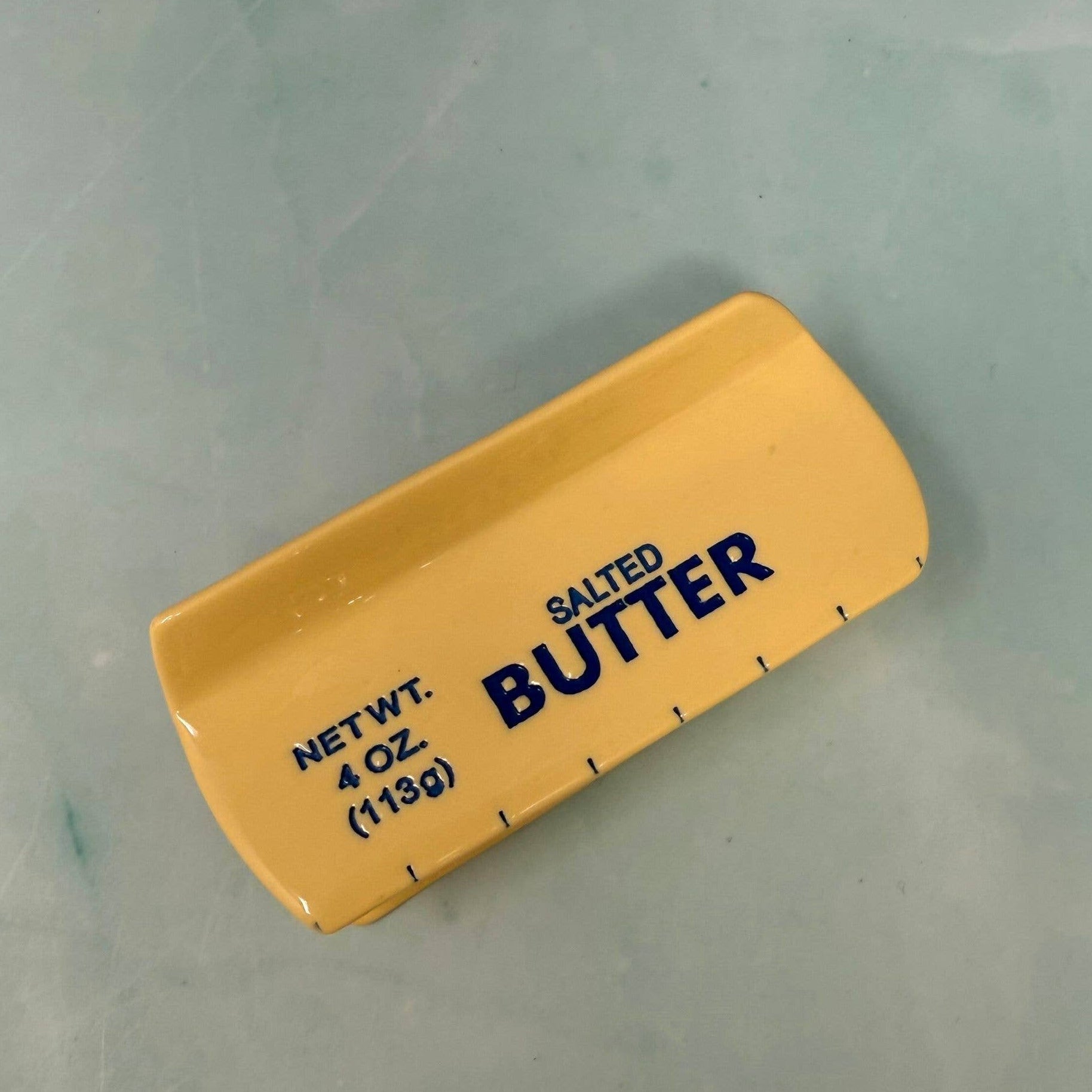 Yellow container of salted butter on a light gray background