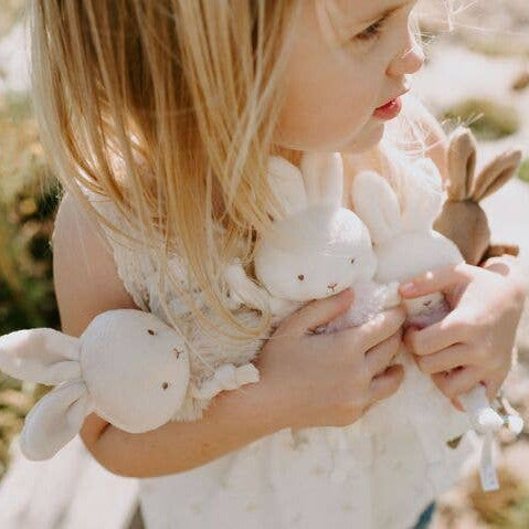Child holding plush bunny toys outdoors