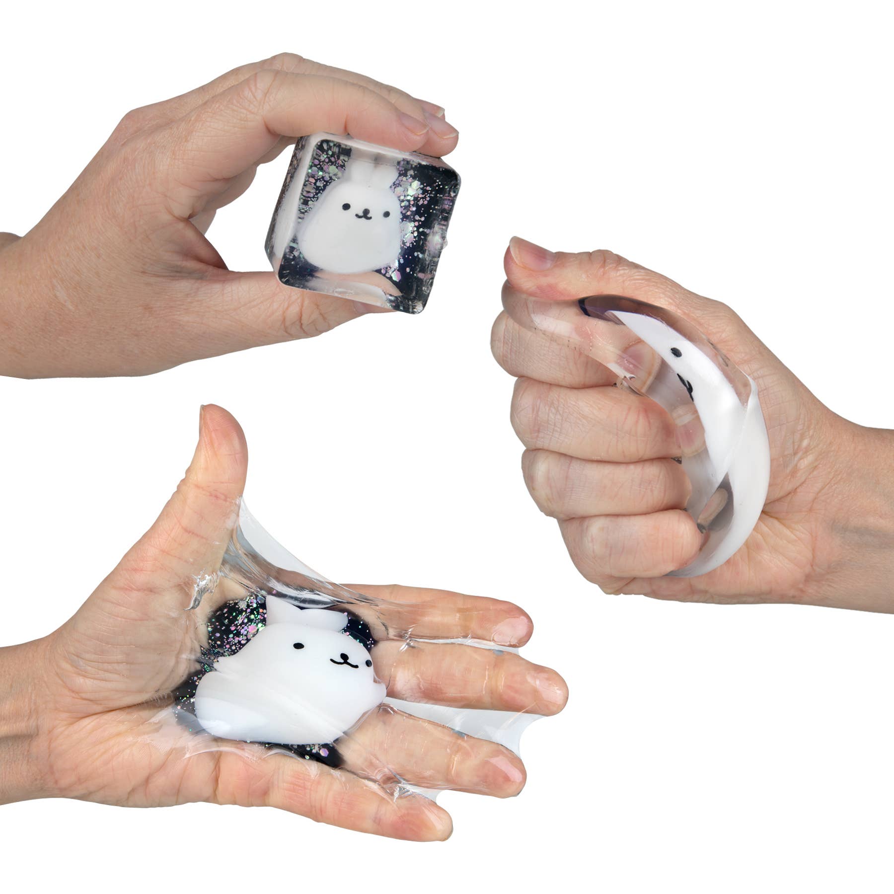 Three hands holding small transparent cubes with white bunny-shaped objects inside on a white background.