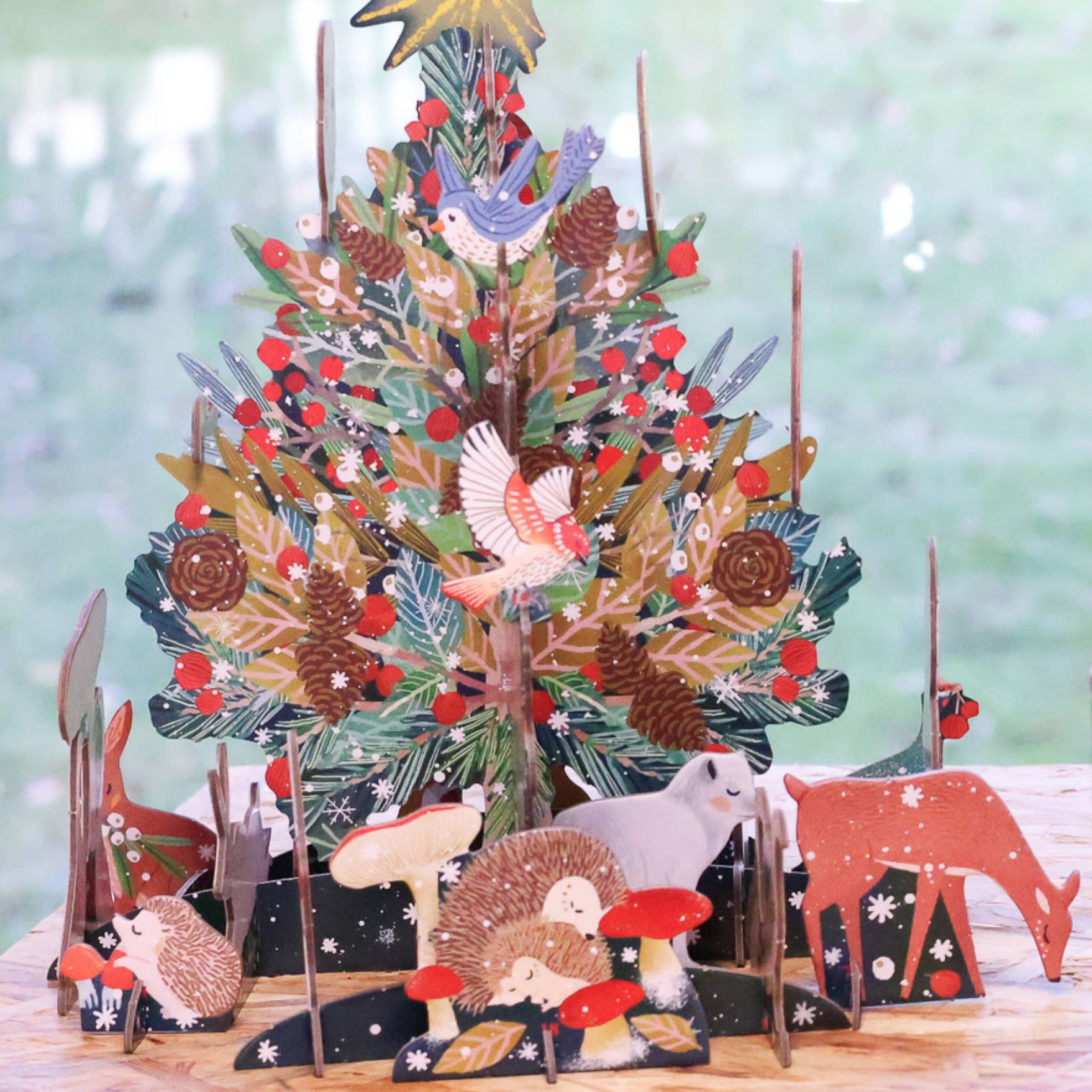 Decorative Christmas tree with animals and nature-themed decorations on a wooden base.