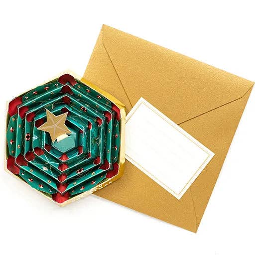 Hexagonal green and red folded card with a gold star on top, next to a brown envelope.