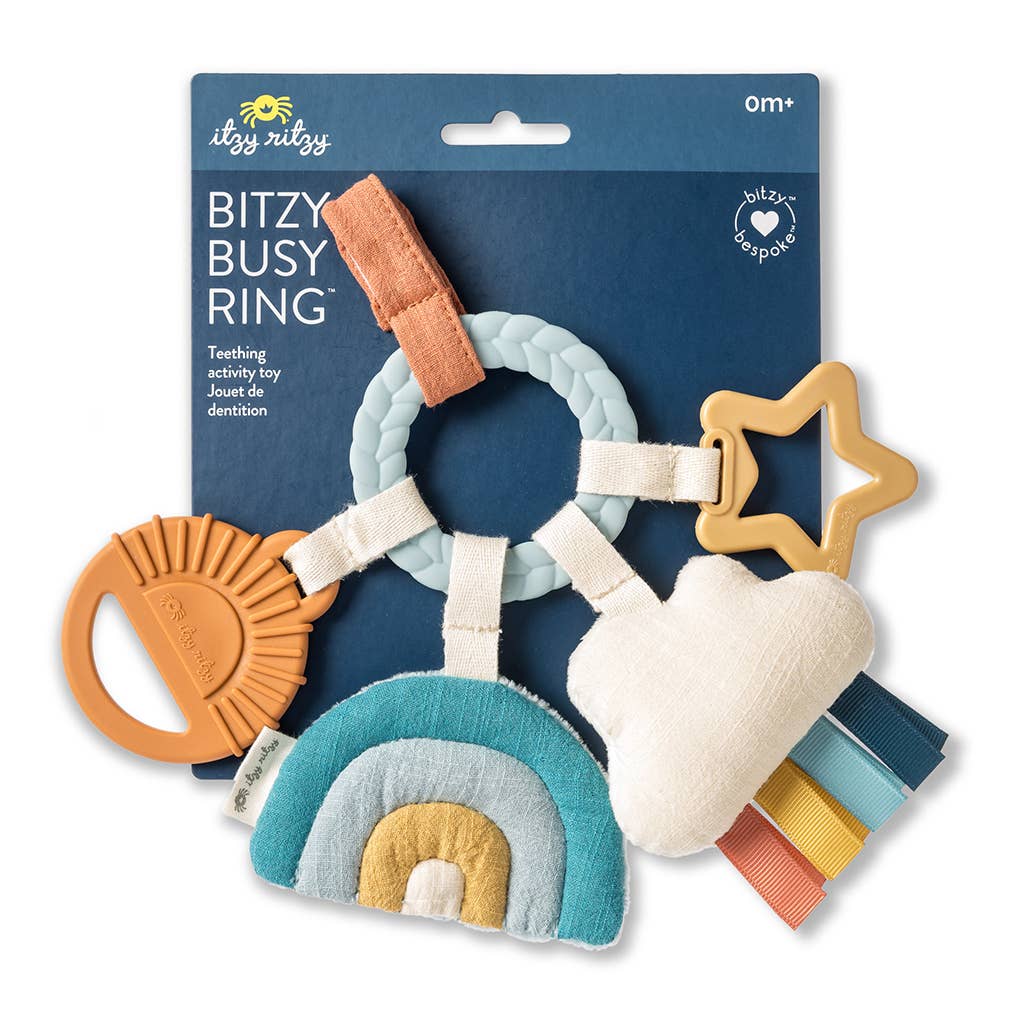 Colorful baby teething ring with various shapes on a blue packaging background