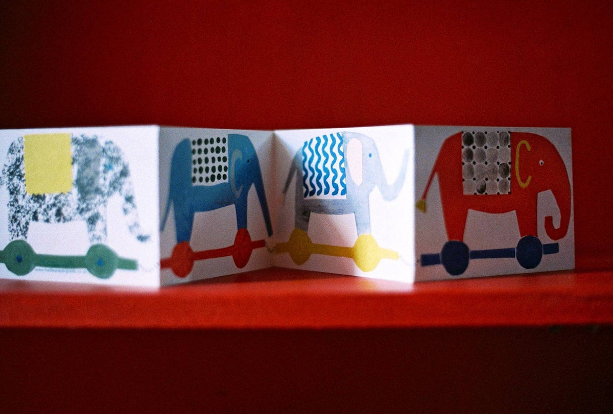 Children's book with colorful elephant illustrations on a red background