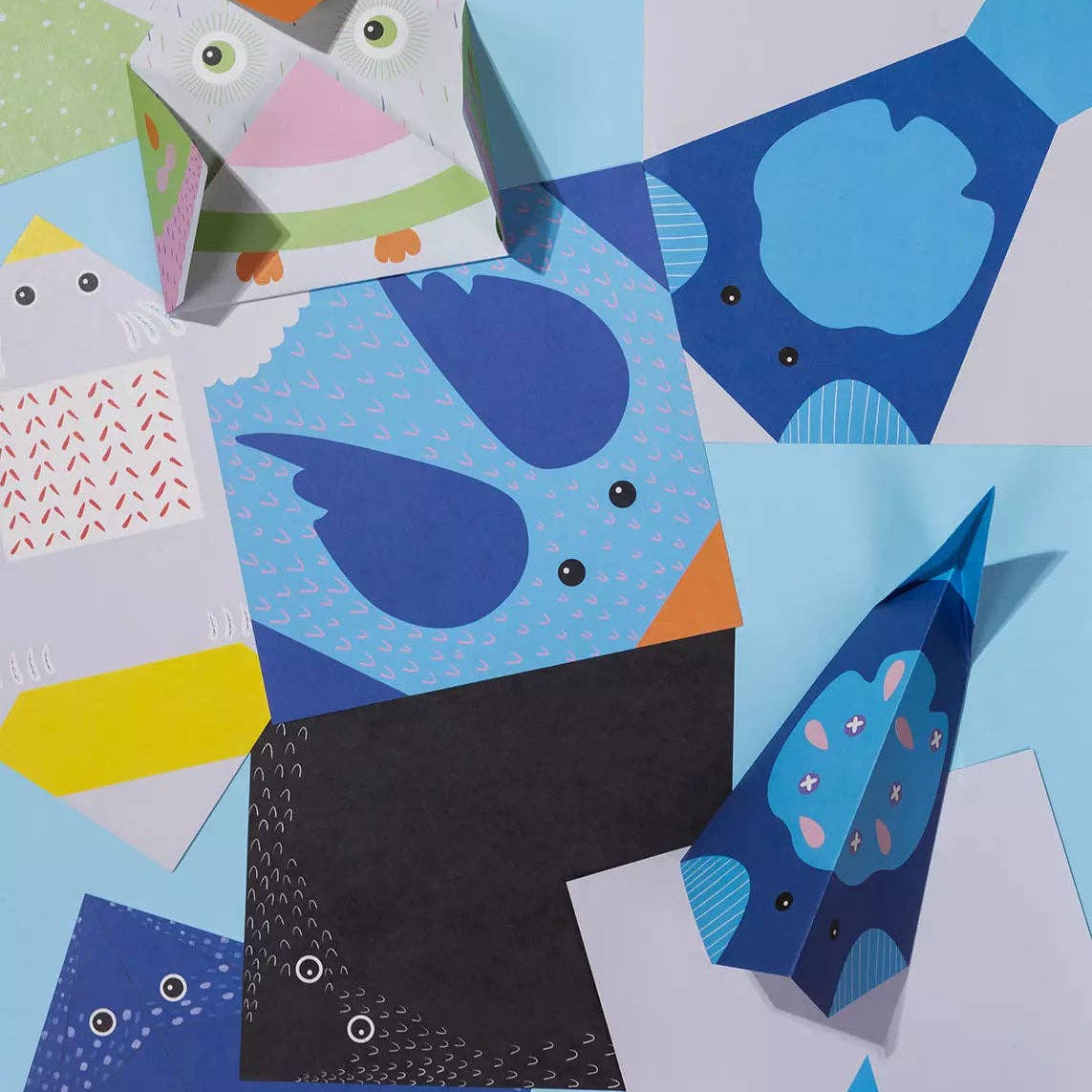 Collage of colorful paper cutouts with geometric shapes and animal designs on a blue background.