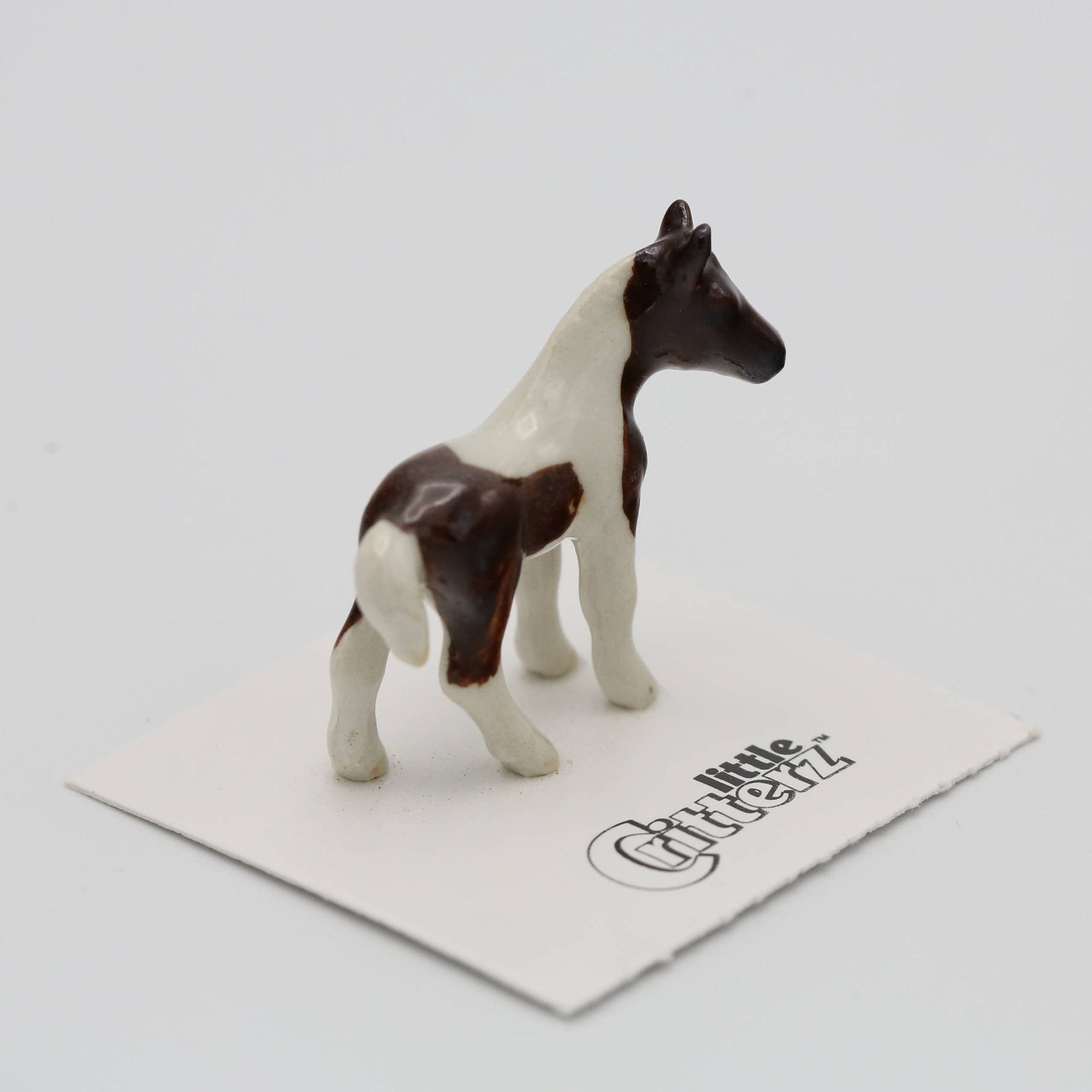 Model horse figurine on a white card with a brand logo on a light gray background