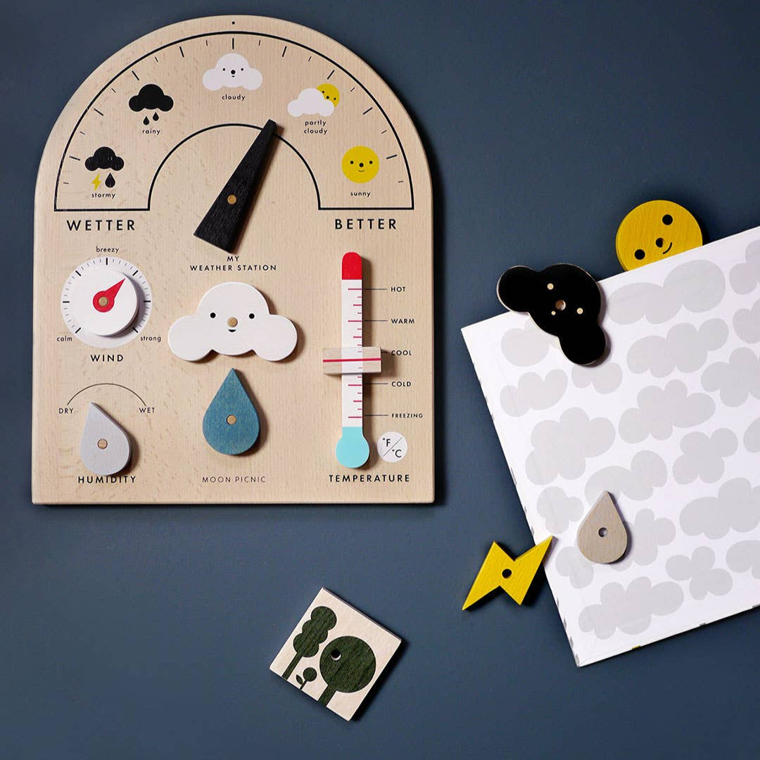Wooden weather station toy with educational elements on a dark blue background