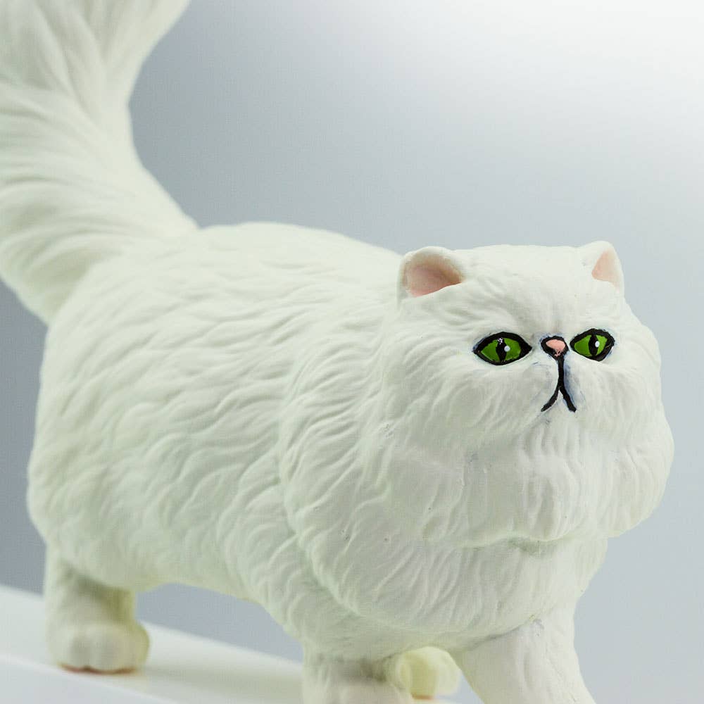 White cat figurine with green eyes on a gray background