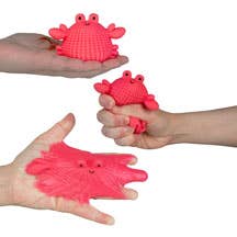 Red silicone crab-shaped molds held by hands against a neutral background