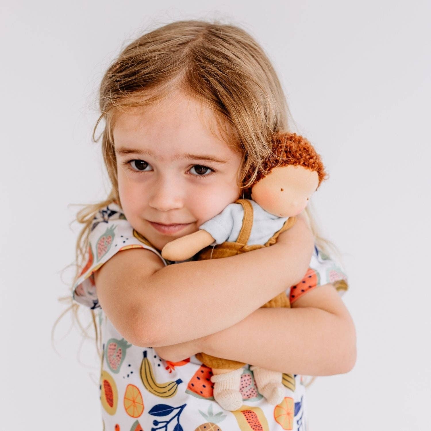 Child holding a doll against a plain background