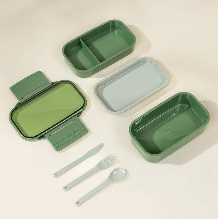 Set of green and gray lunch boxes with utensils on a beige background