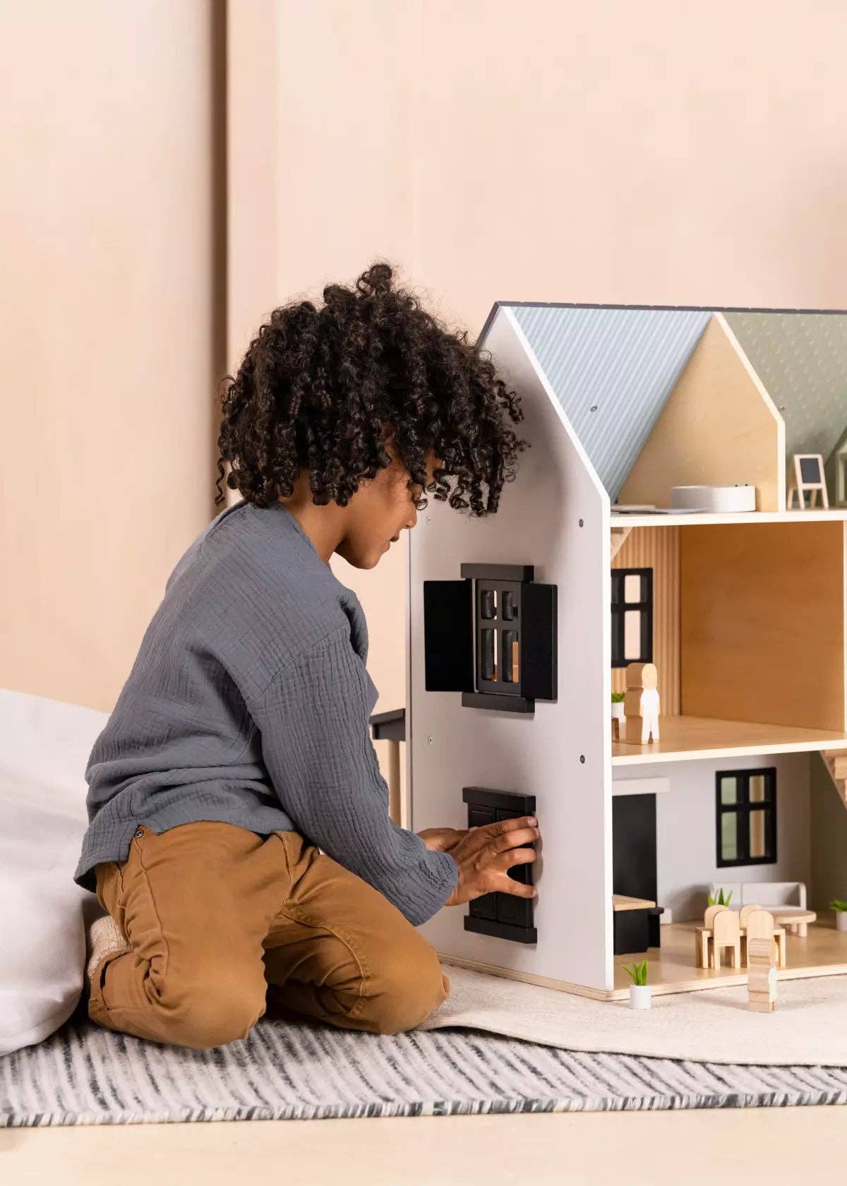Child playing with a dollhouse on a carpeted floor.
