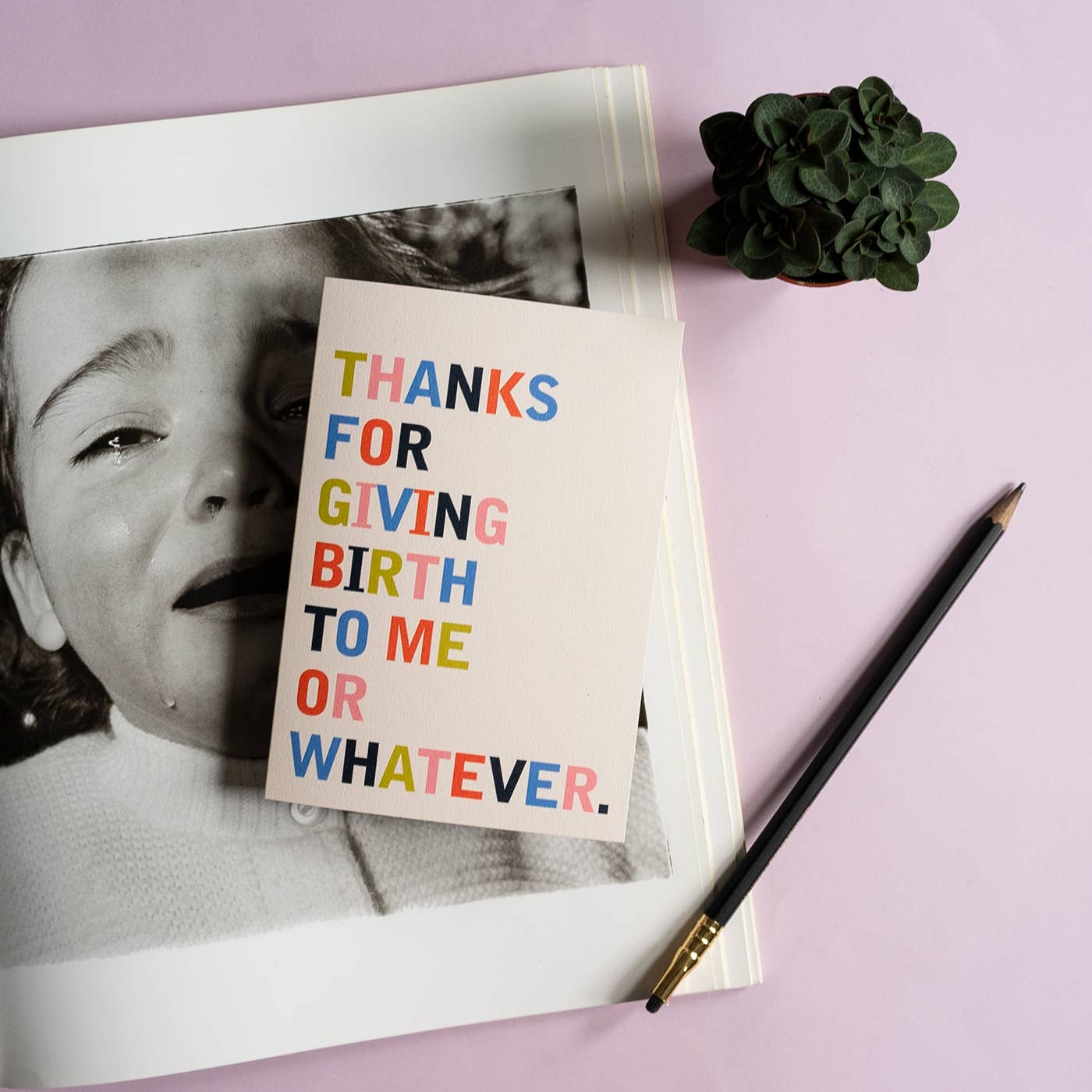 Notebook with a card reading 'Thanks for giving birth to me or whatever' on a purple background.