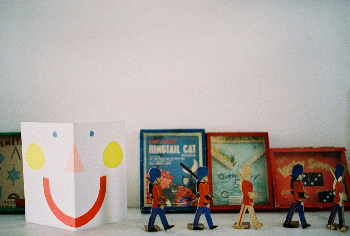 Colorful toy figures and a smiley face card on a white surface with a plain background