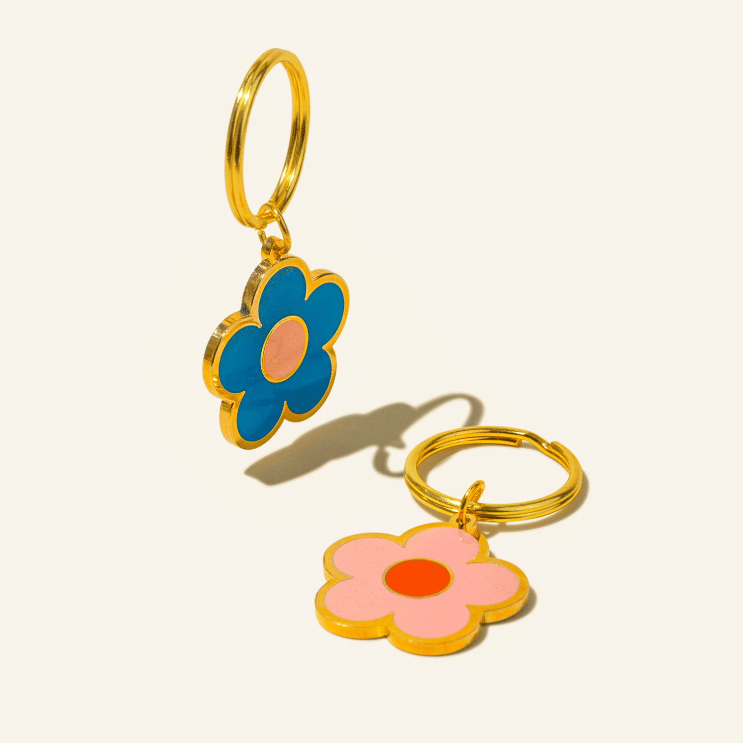 Flower-shaped keychains with gold rings on a light beige background