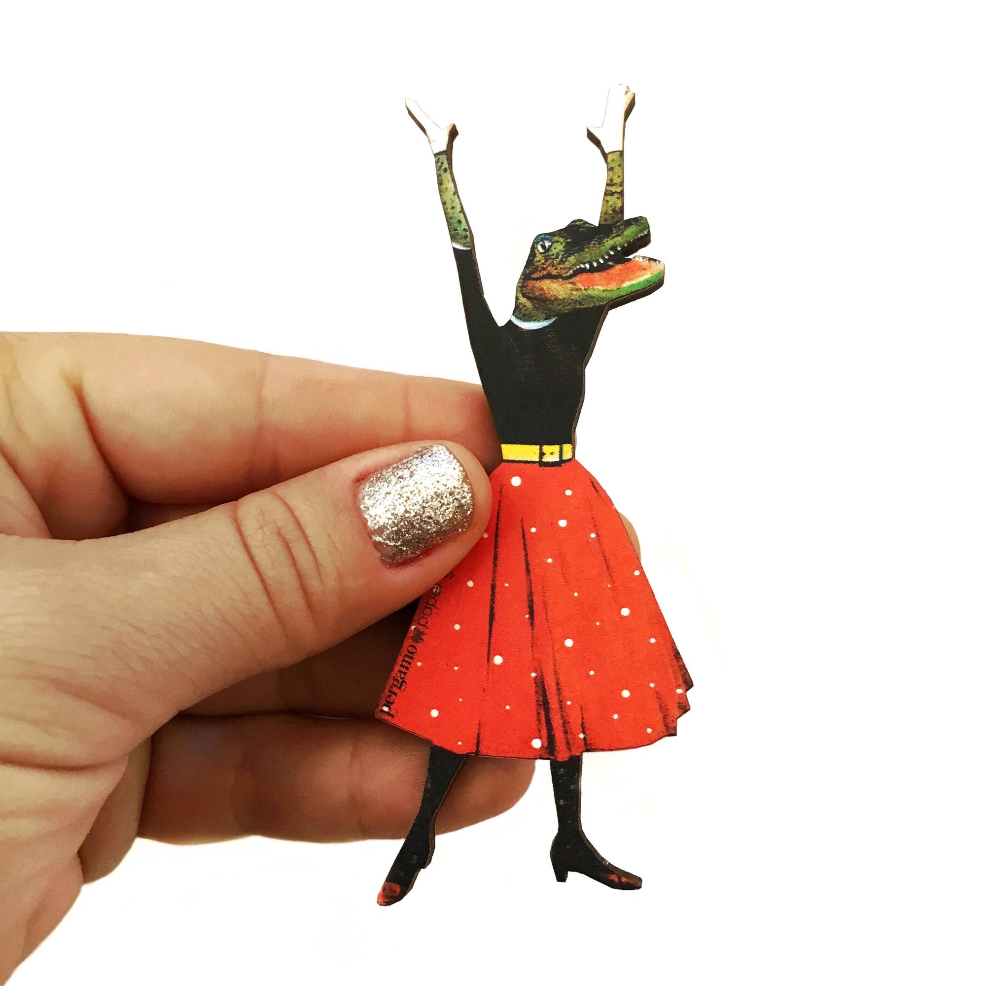 Hand holding a paper figurine of a creature with a red dress on a white background