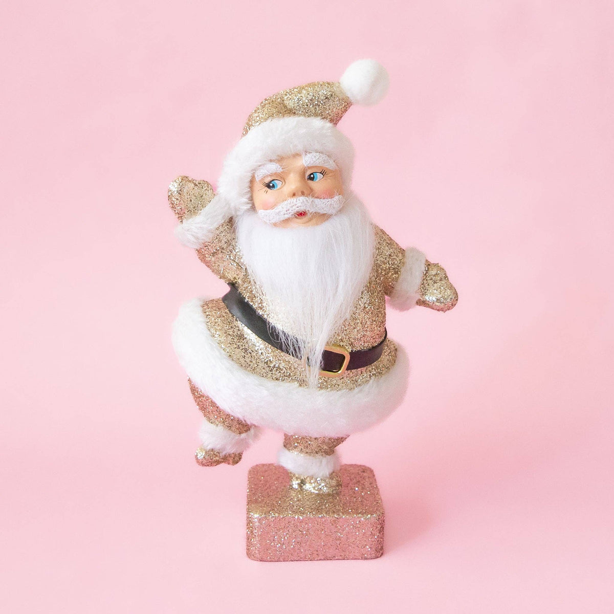Decorative Santa figurine with gold and white attire on a pink background