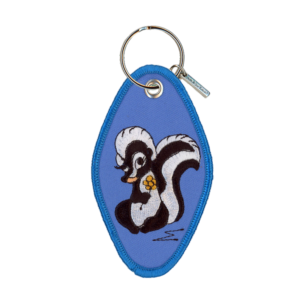 Keychain with a cartoon skunk design on a blue background