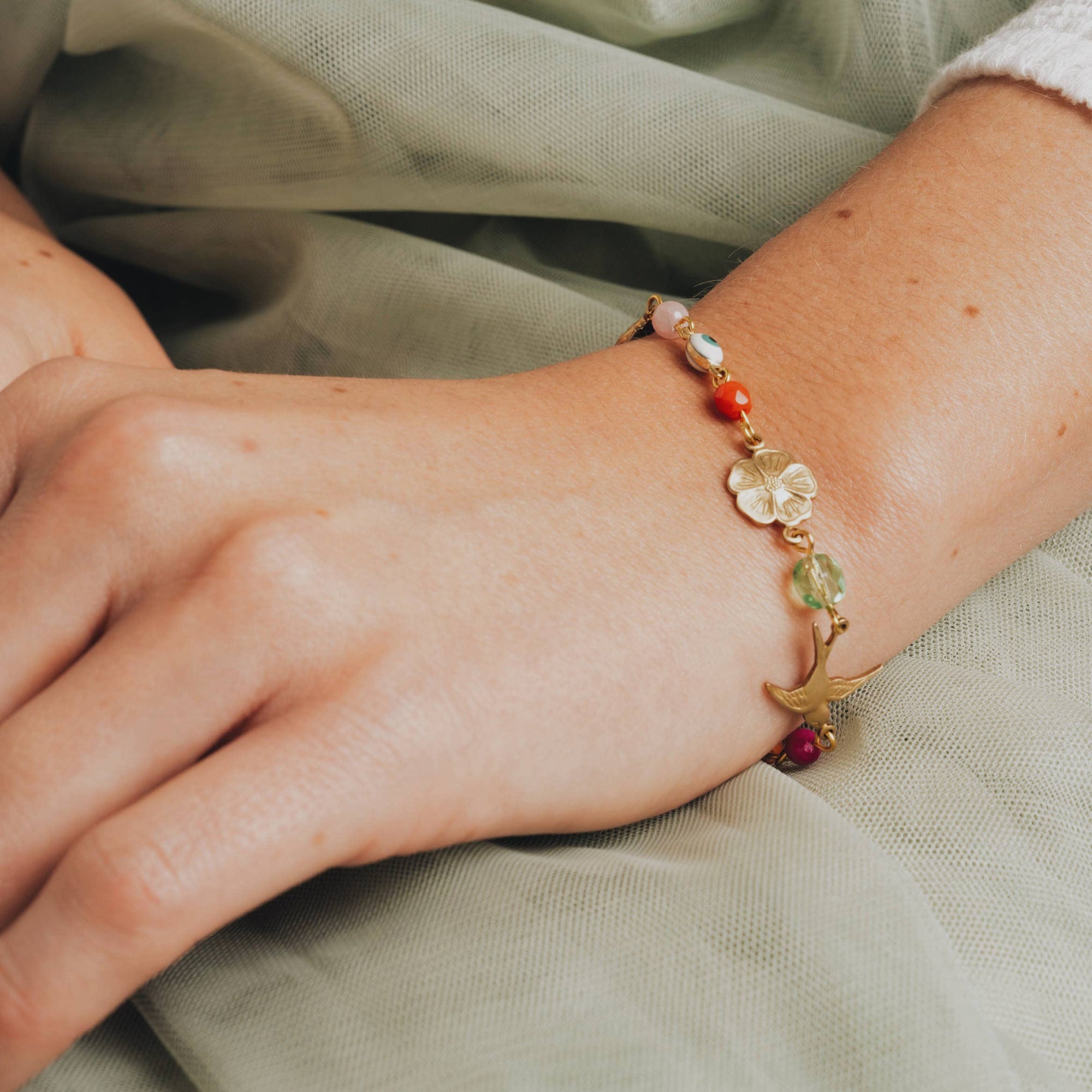 Close-up of a wrist wearing a colorful beaded bracelet on a light fabric background