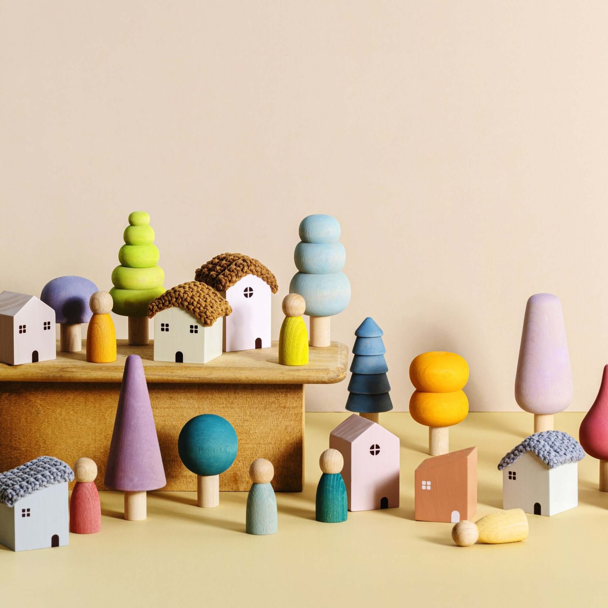 Colorful wooden toy village with houses and trees on a beige background