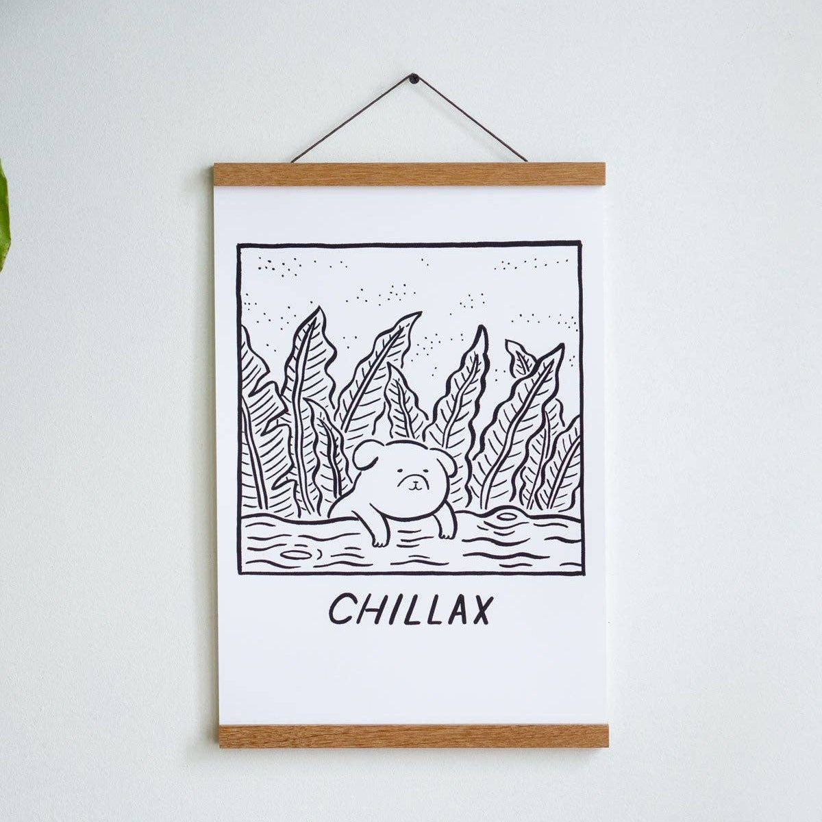 Framed artwork with a bear and text 'CHILLAX' on a white wall.