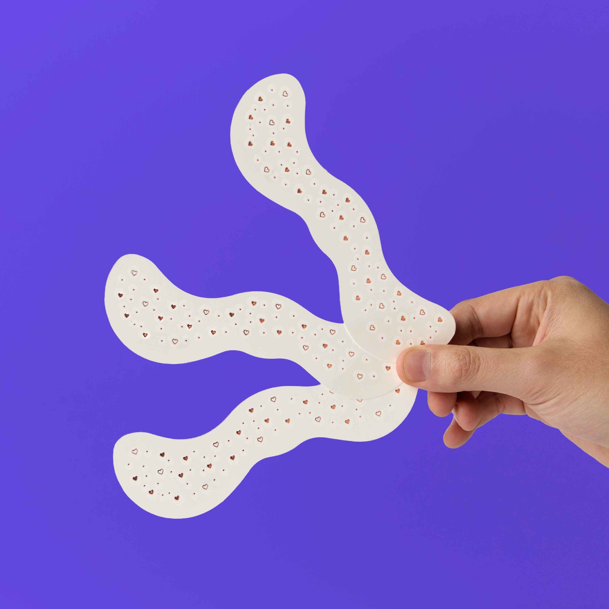 Hand holding a white, textured object against a purple background