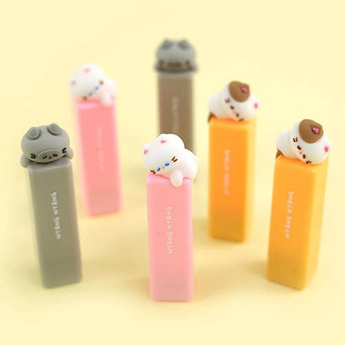 Set of five colorful lip balms with animal-shaped tops on a yellow background