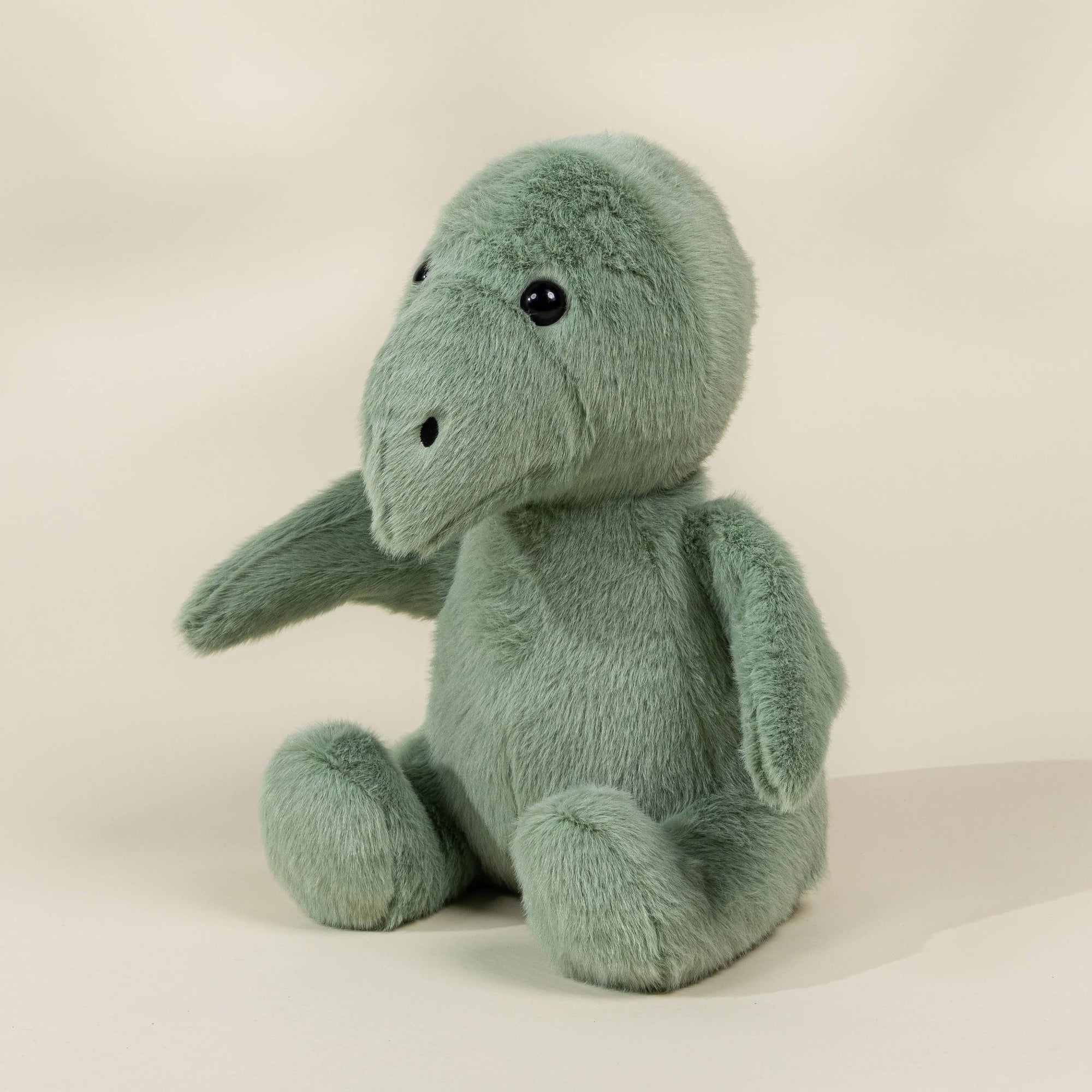 Green plush toy elephant on a beige background