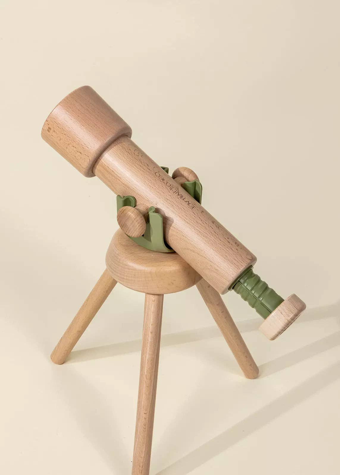 Wooden toy telescope on a stand with a beige background