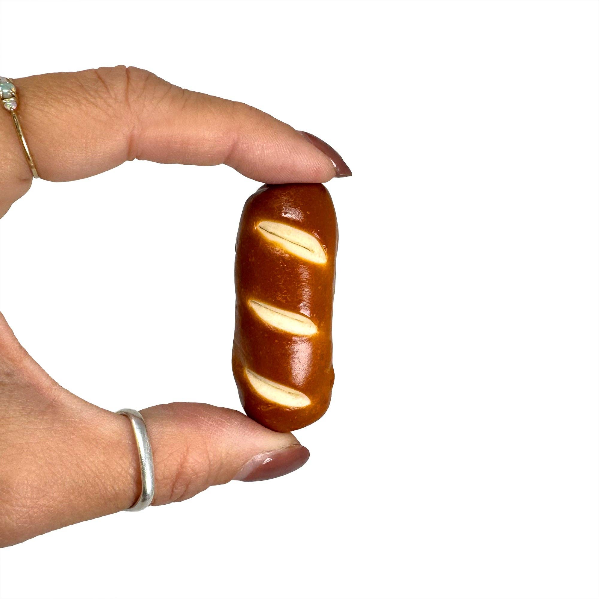 Hand holding a chocolate candy shaped like a loaf of bread on a white background