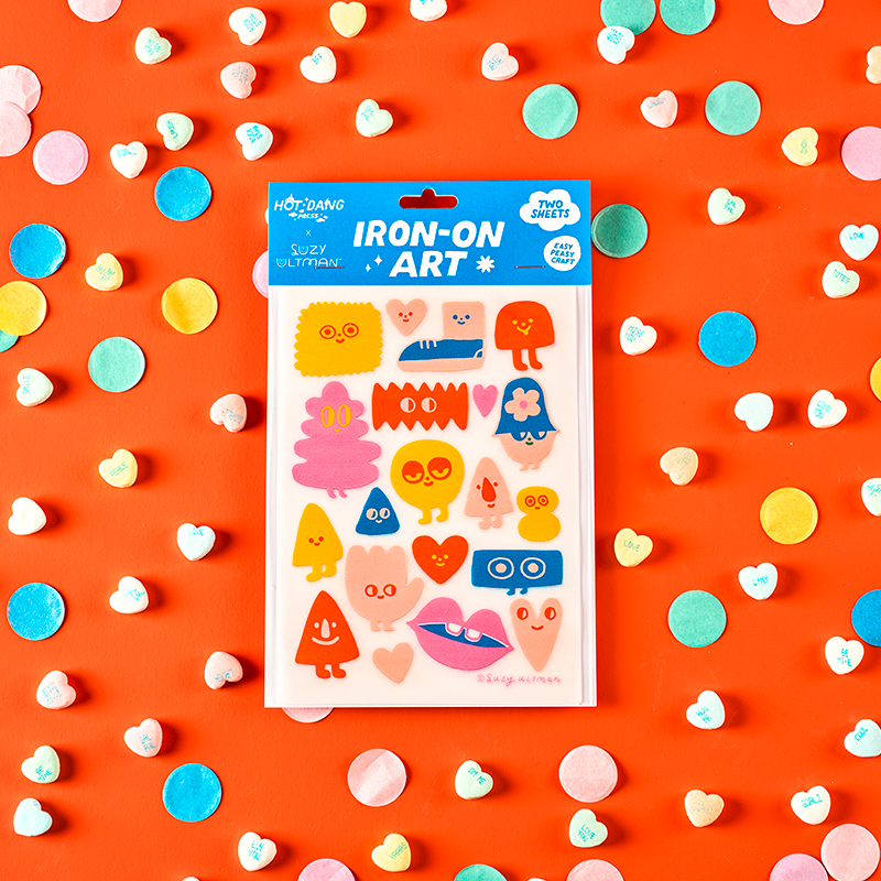 Pack of iron-on art stickers on an orange background with colorful confetti