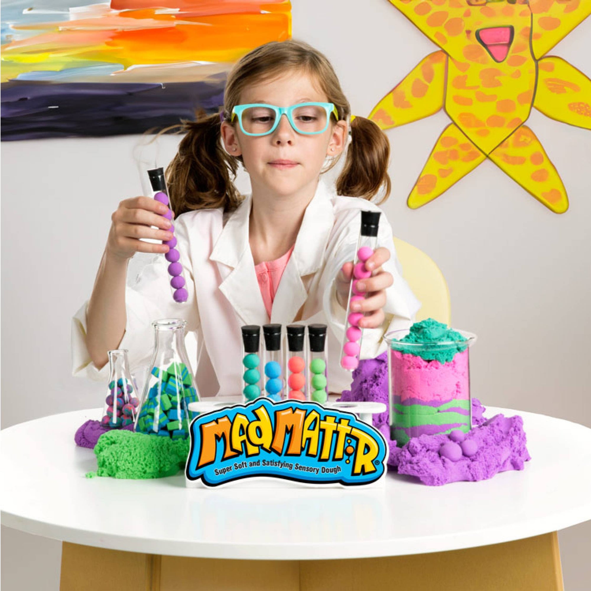 Child in a science-themed setting with colorful experiment materials and 'Mad Mater' branding.
