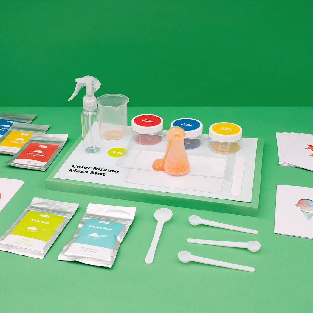 Color mixing kit with packets, containers, and tools on a green background